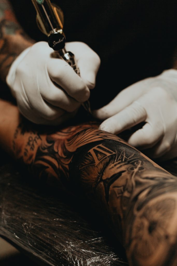 Photo d'un tatoueur en train de tatouer un client