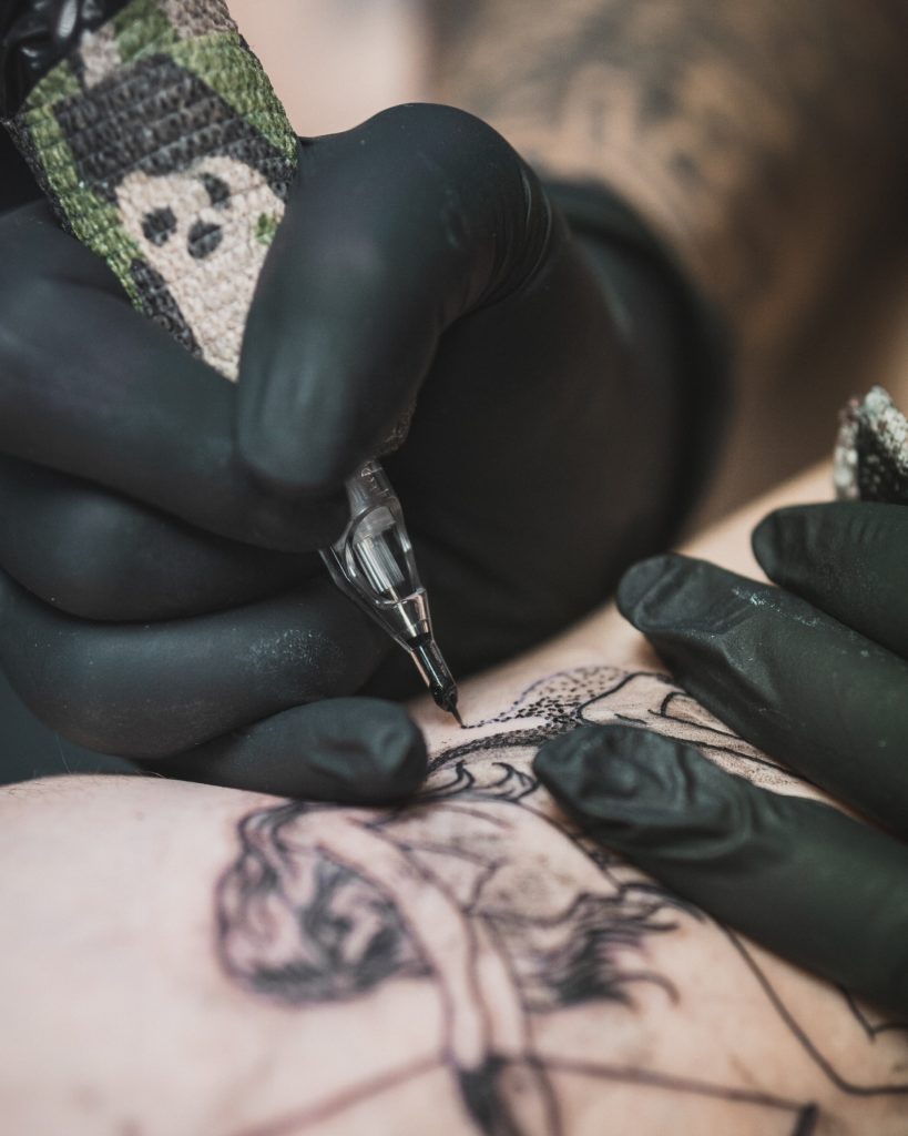 Photo d'un tatoueur en train de tatouer un client
