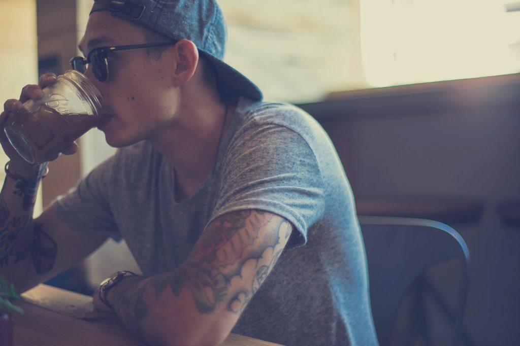 un homme qui boit son café avec le bras tatouer