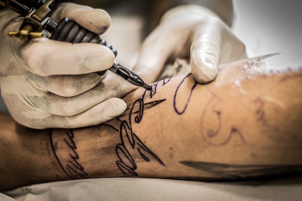 Photo d'un tatoueur en train de tatouer un client